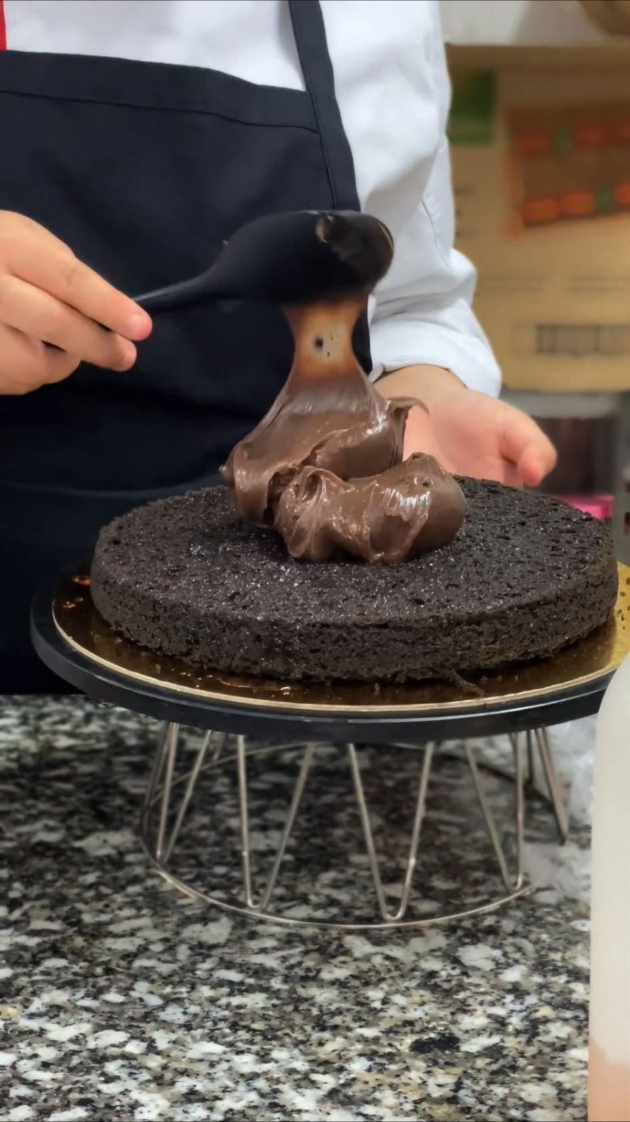 Creme de chocolate a ser espalhado sobre a massa de bolo de chocolate por um pasteleiro dos Bolos da Marta